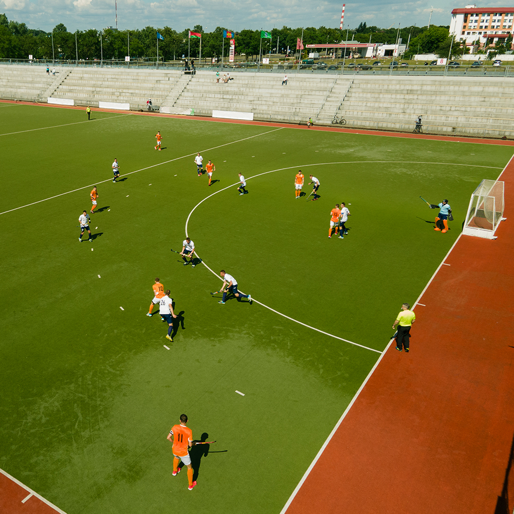 Players and fans at a community football match at sunset